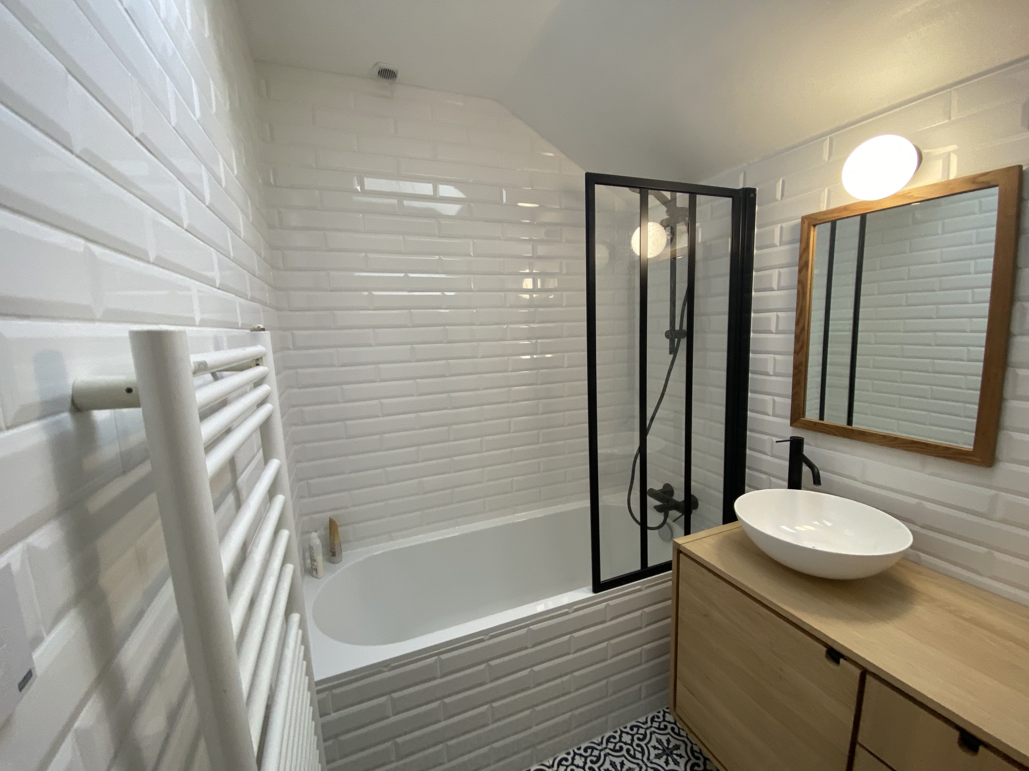 Salle de bain moderne avec baignoire, douche et carrelage métro blanc